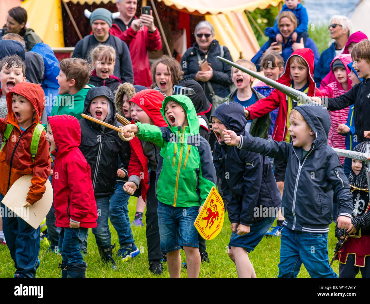 Linlithgow Palace, West Lothian, Schottland, Großbritannien. 30. Juni 2019. Ritterspiele in Linlithgow Palace: Historische Umgebung Schottland präsentieren ihre jährlichen Mittelalterlichen Familientag an der Schale. Veranstaltungen gehören Unterhaltung für die ganze Familie mit einem Kinder- Armee schiltron. Kinder punkt Spielzeug Schwerter und Schreien Stockfoto