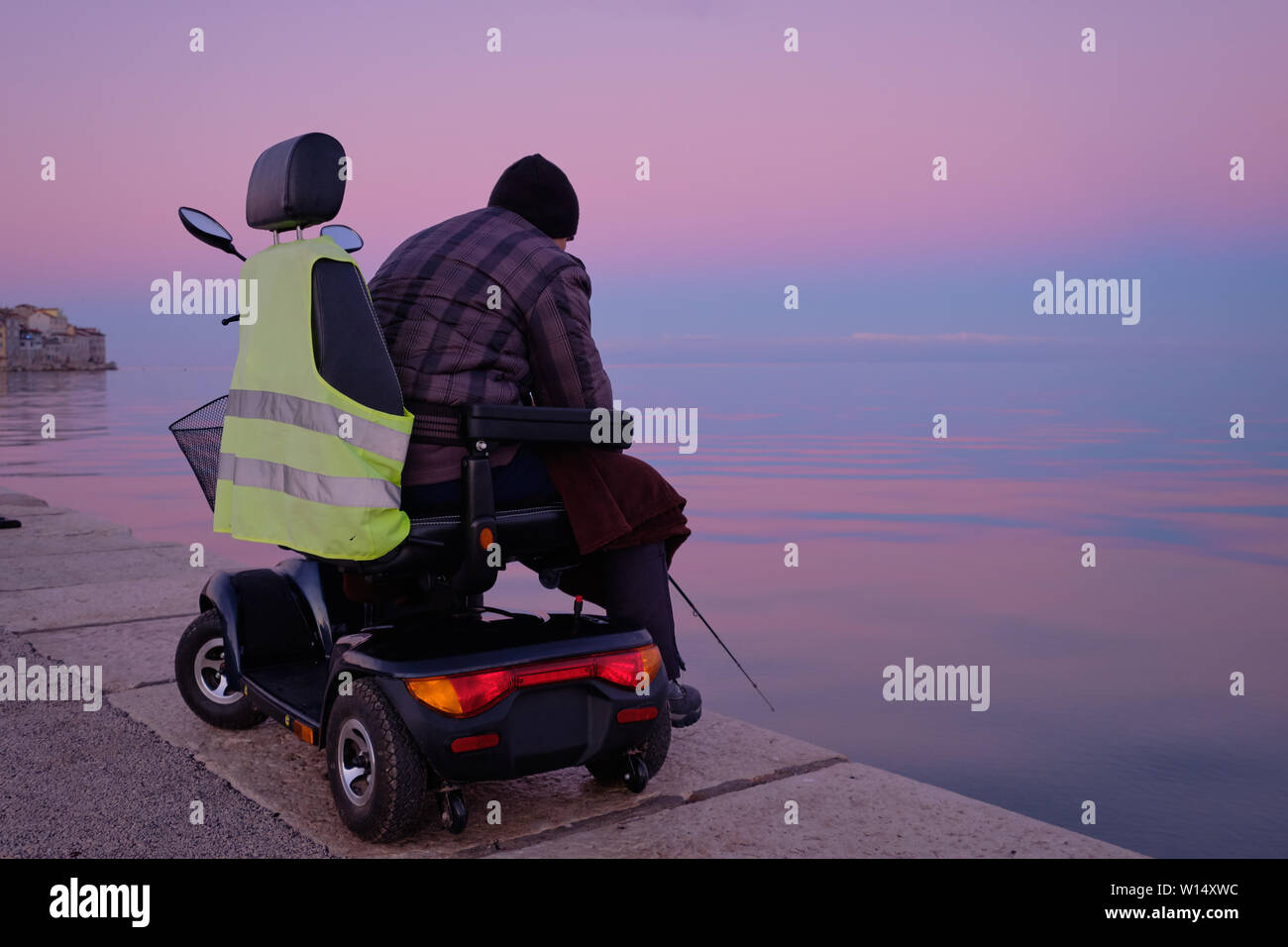 Person mit Hilfe eines persönlichen Mobilität scooter, ihm zu erlauben, die normale Tätigkeit zu tun eingeschränkter Mobilität. Ihn hier Angeln in den frühen Morgenstunden Stockfoto