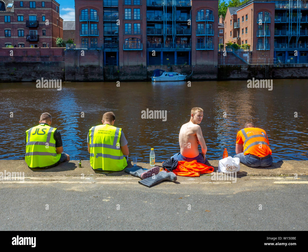 Vier Männer von einer Baustelle ruht und mit Essen und Trinken am Ufer des Flusses Ouse im Zentrum von York Stockfoto