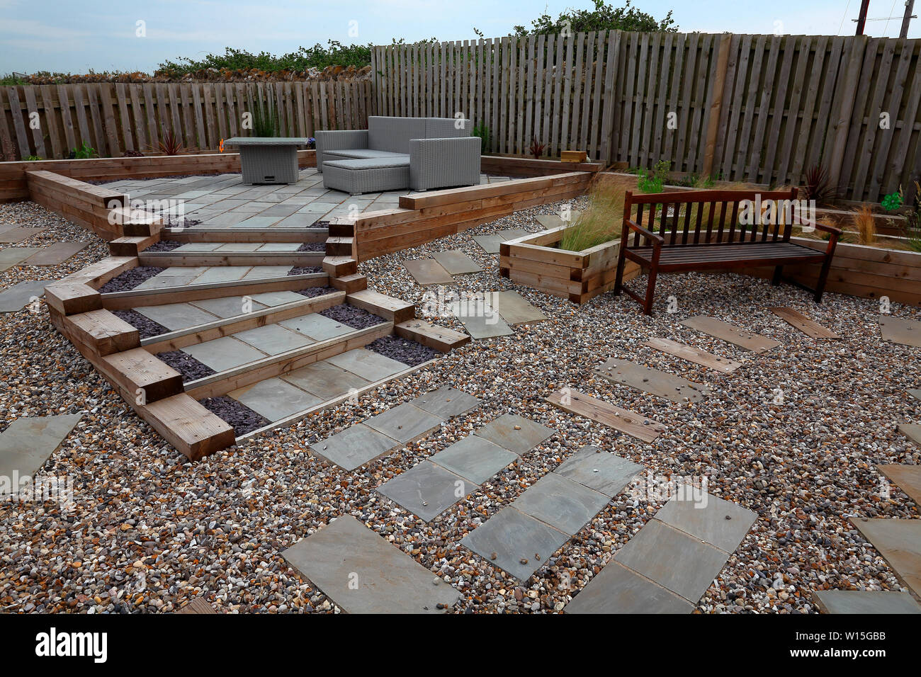 Ein Designer Garten mit großen Mengen von Holzschwellen isoliert wachsenden Betten zu bilden mit Pflanzen jetzt etabliert. Stockfoto