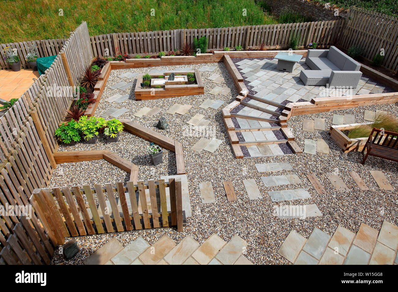 Ein Designer Garten mit großen Mengen von Holzschwellen isoliert wachsenden Betten zu bilden mit Pflanzen jetzt etabliert. Stockfoto