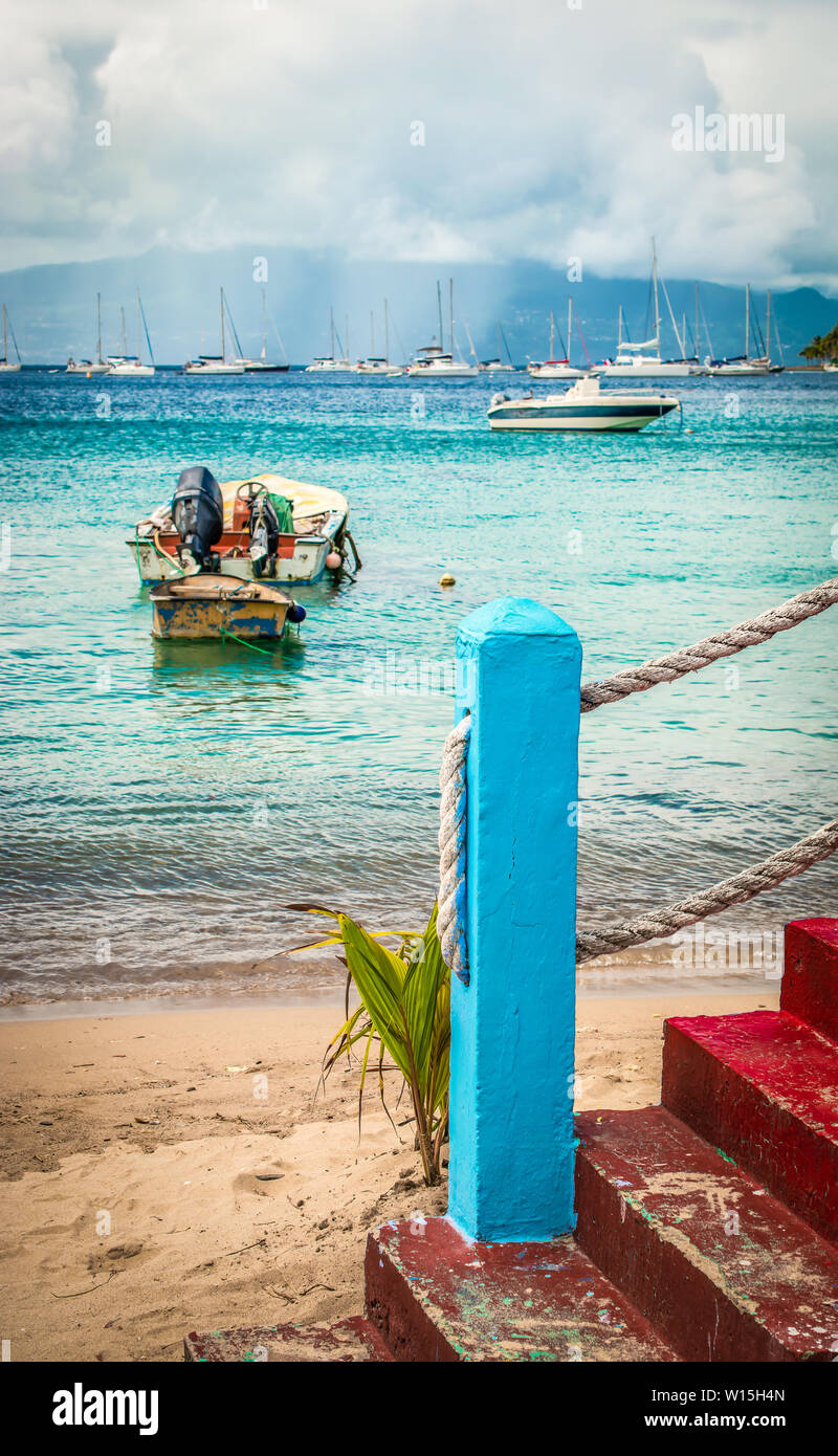 Rot lackiert alte Steintreppe mit Cyan Blau Pol und starke Schnur am Strand. Angeln Boot auf dem Wasser. Im Hintergrund Regenwolken. Terre-de-Ha Stockfoto