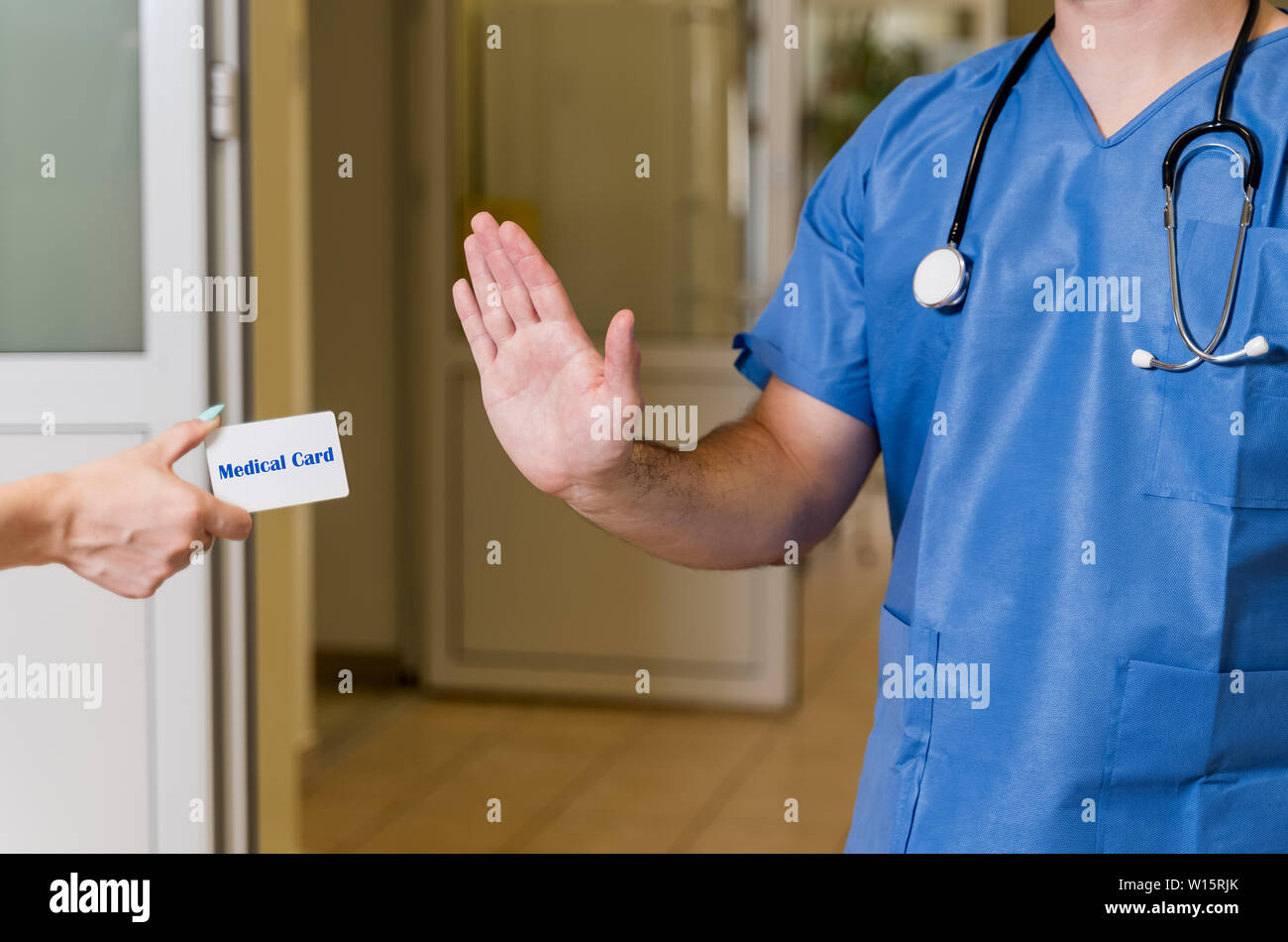 Mittleren Alters, kaukasischen weißen, männlichen Arzt in Scrubs mit Stethoskop verweigerung Medical Card, verschwommenes Krankenhaus Flur im Hintergrund Stockfoto