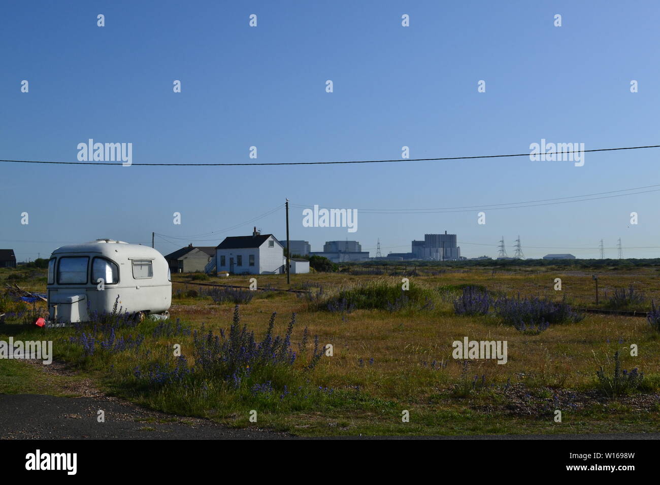 Ein Wohnwagen, Hütten, vipers bugloss Blumen und das Kernkraftwerk in Dungeness, Kent, an einem Sommertag. Stockfoto