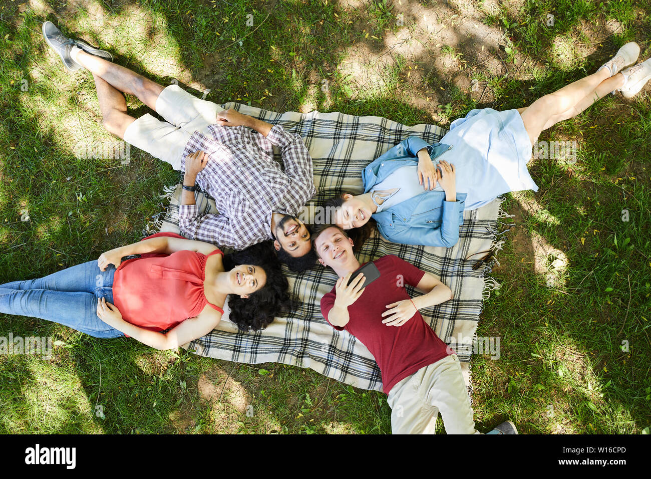 Oben Blick Porträt der Gruppe der Freunde liegen auf Decke und geniessen Sie ein Picknick auf grünem Gras und unter selfie Foto, Kopie Raum Stockfoto