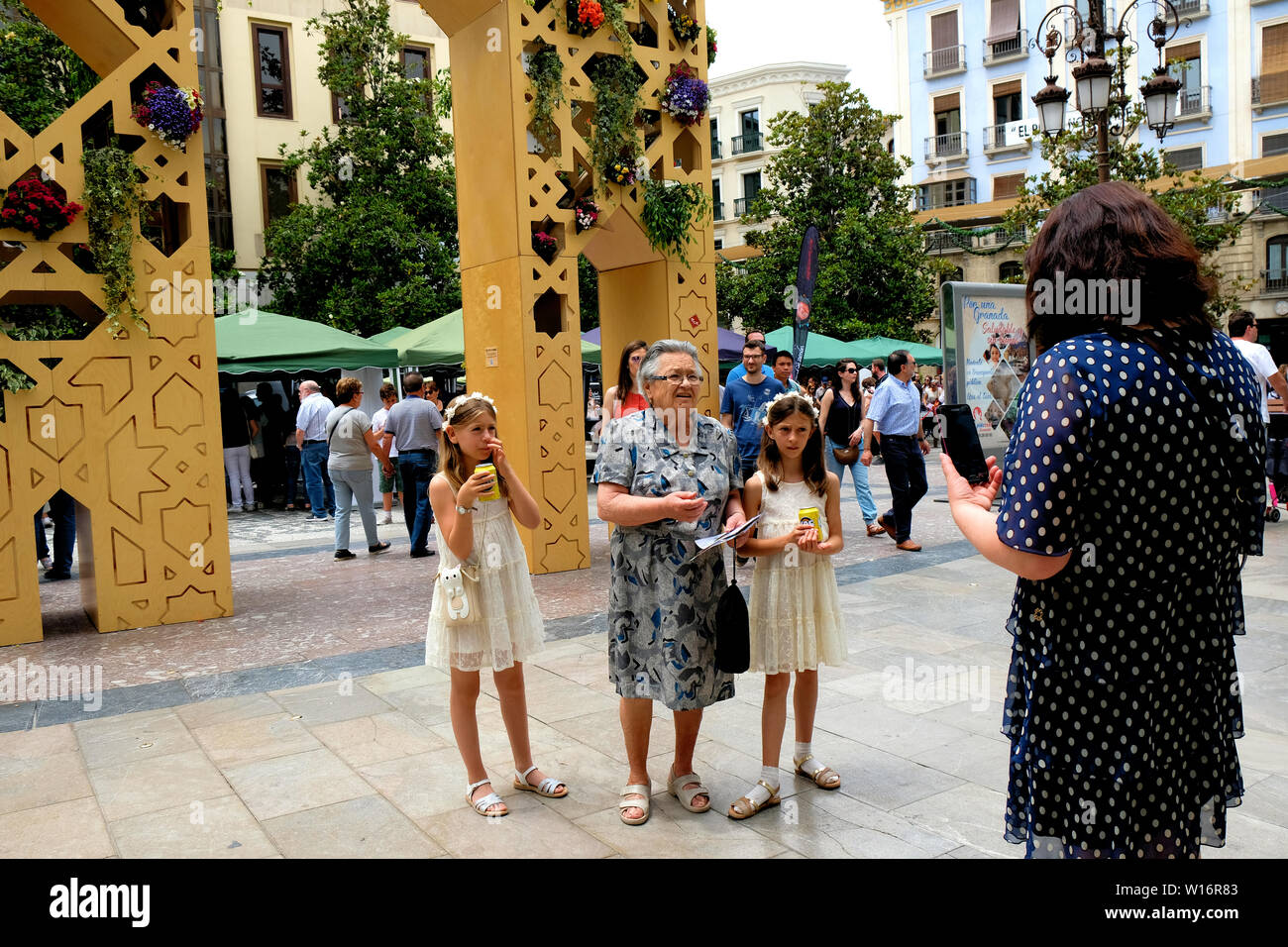 Zwilling Mädchen und ihre Großmutter an ihre Mutter in einer Plaza in Granada, Spanien; drei Generationen: Enkelinnen, Oma und Mama. Stockfoto