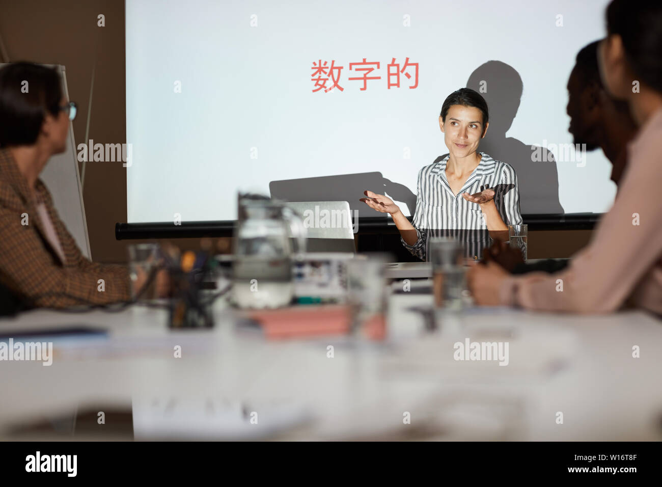 Attraktive junge Frau Ausbildung Klasse auf chinesische Kommunikation: Sie zuckte mit den Schultern, während das Erklären, Informationen in der Sitzung Stockfoto