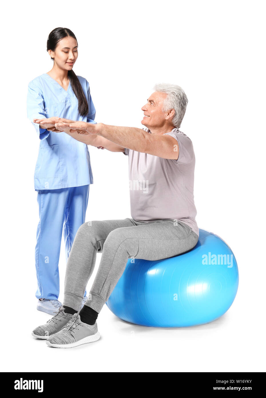 Jungen asiatischen Physiotherapeuten arbeiten mit reifer Mann auf weißem Hintergrund Stockfoto