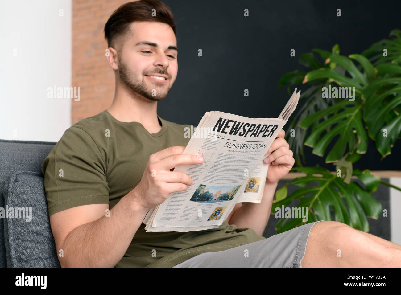 Schöner mann lesen Zeitung zu Hause Stockfoto