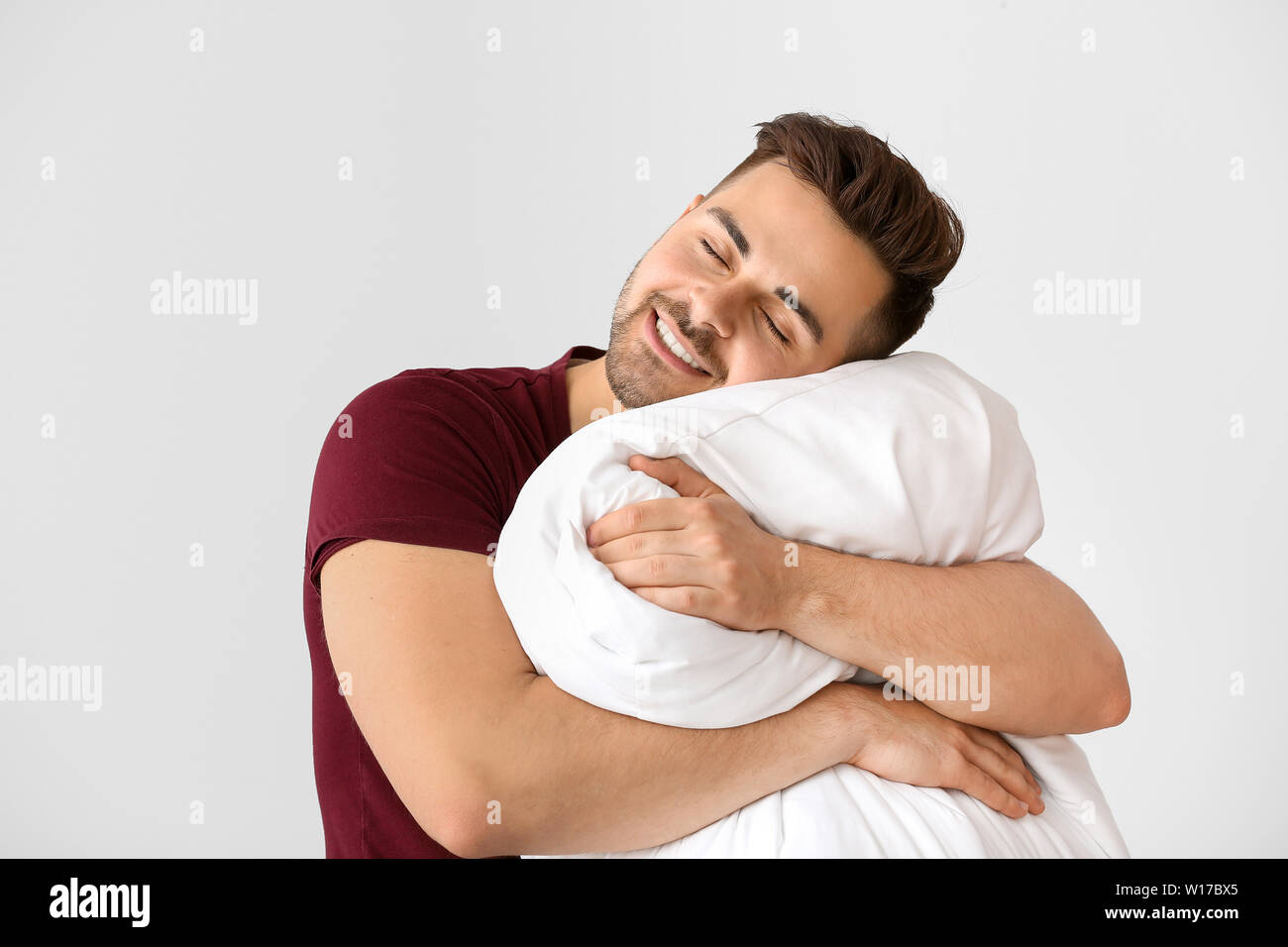 Schöner Mann umarmen Kissen gegen den weißen Hintergrund Stockfotografie -  Alamy