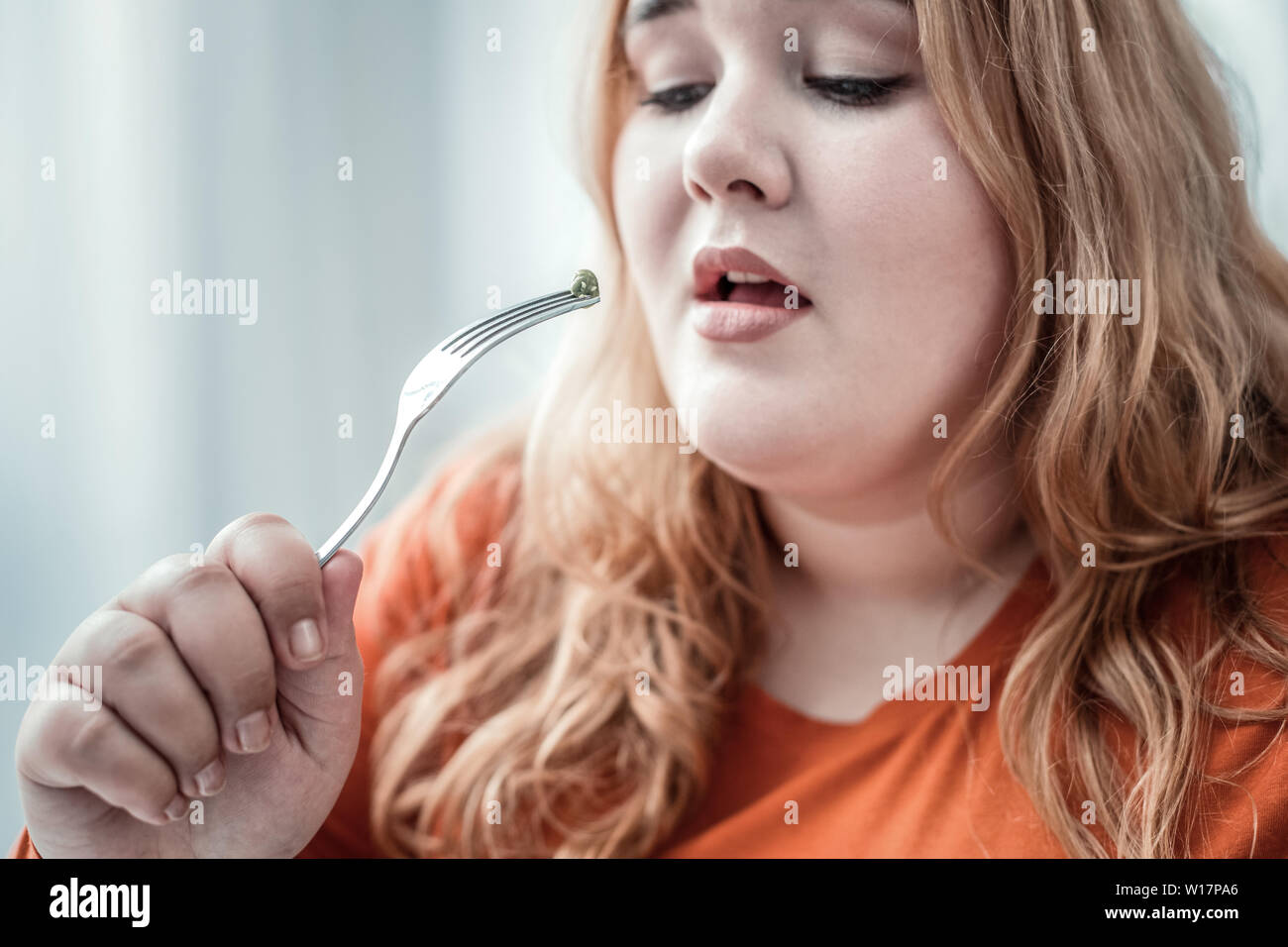 Aufmerksame pralle Mädchen an grüne Erbsen starrte Stockfoto