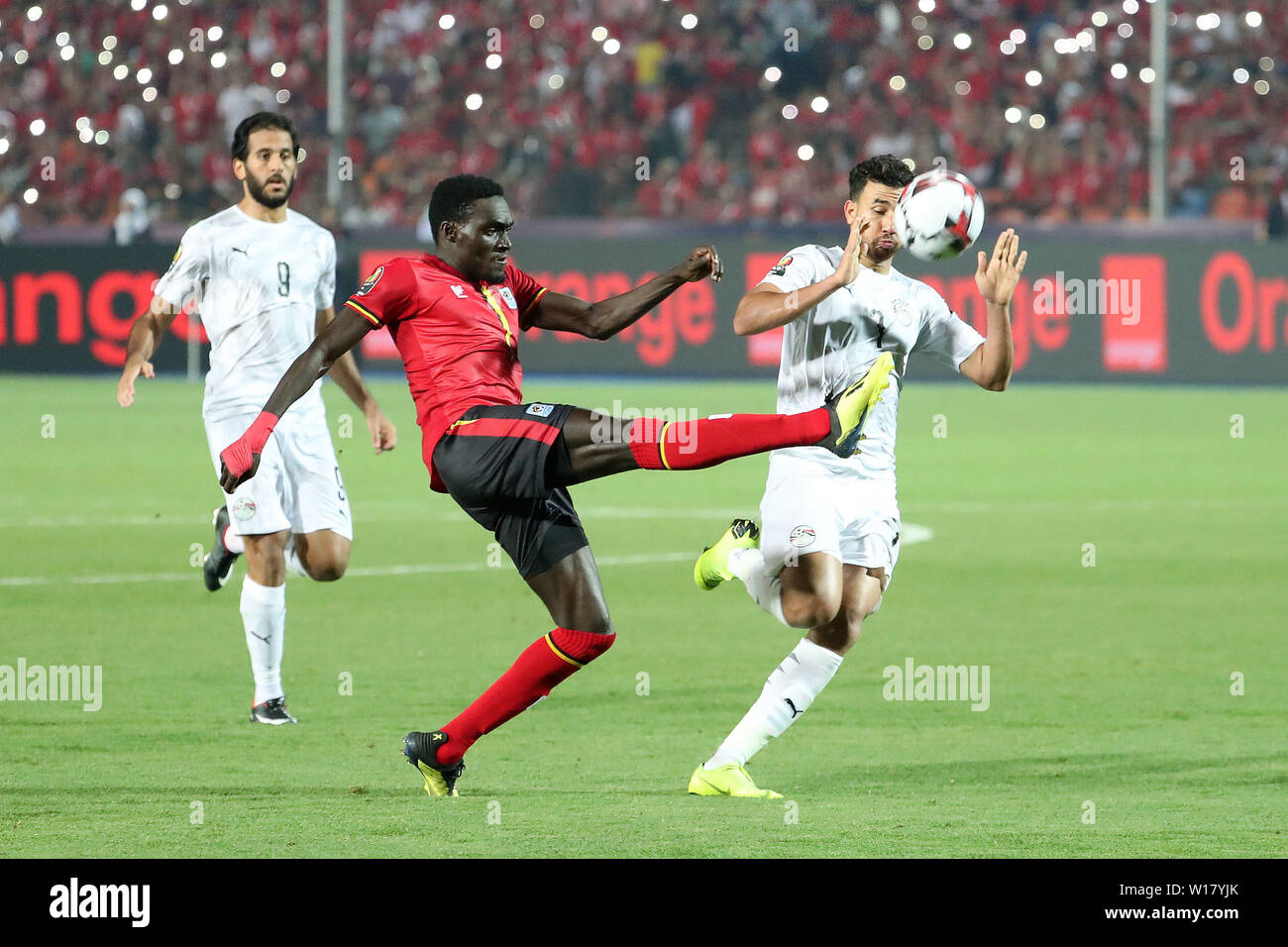 Kairo, Ägypten. 30. Juni, 2019. Timothy Dennis Awany (C) der Uganda Mias mit Mahmoud Ahmed Ibrahim Hassan von Ägypten während der 2019 Afrika Cup der Nationen, eine Übereinstimmung in Kairo, Ägypten, 30. Juni 2019. Credit: Wang Teng/Xinhua/Alamy leben Nachrichten Stockfoto