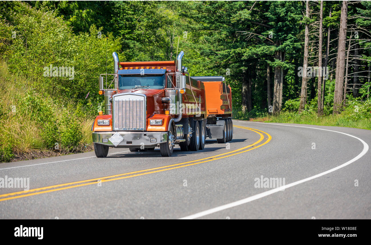 Big Rig leistungsstarke Industrie braun Kipper semi Traktor mit zwei dump  Trailer für schwere Lasten, die auf den kurvenreichen Straße in grüne Bäume  Wald wi Tuck Stockfotografie - Alamy