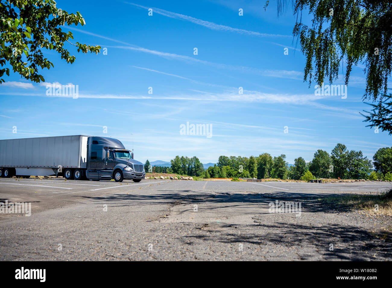 Big Rig Dunkelgrau professionelle industrielle Motorhaube Long Haul Semi Truck mit trockenen van Auflieger für den Transport von verpackten kommerziellen Ladung steht i Stockfoto