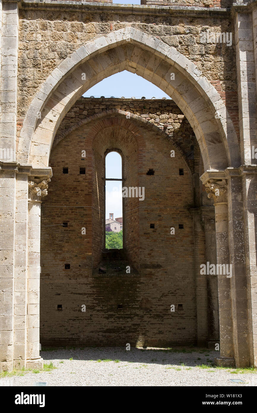 Detail eines Bogens in San Galgano Abbey mit einem Fenster mit Blick auf das nächste Gebäude. Vertikale erschossen. Stockfoto