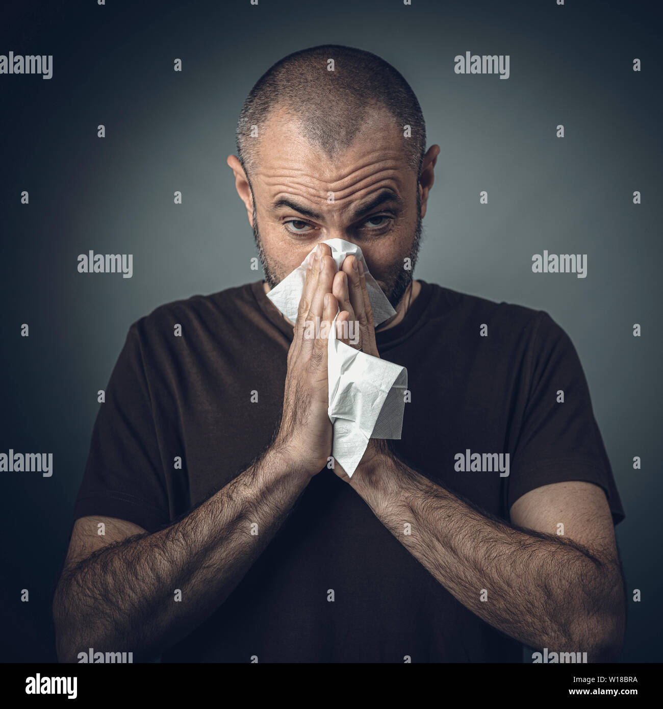 Porträt eines Mannes, der seine Nase weht mit einem Gewebe. Blick in die Kamera. Konzept von Unwohlsein und Allergie. Stockfoto