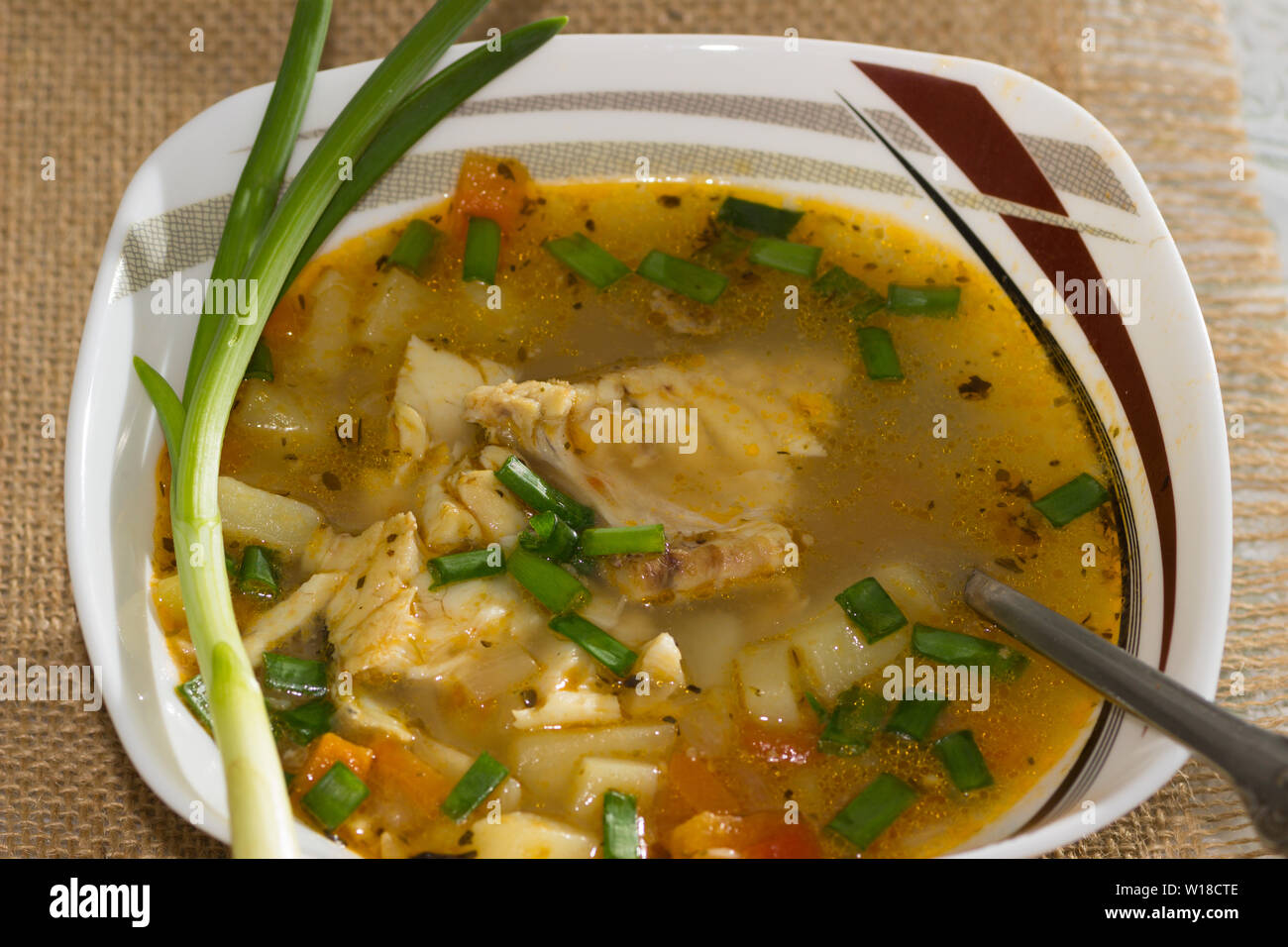 Schüssel von Kabeljau, Tomaten und grüne Zwiebel Suppe mit einem Stück Roggenbrot auf eine Serviette Stockfoto