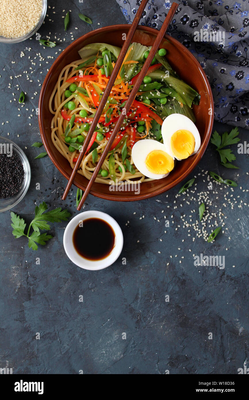 Nudeln mit Gemüse und Eier in der Schale auf dunklem Hintergrund. Ansicht von oben mit der Kopie. Asiatische Küche. Stockfoto