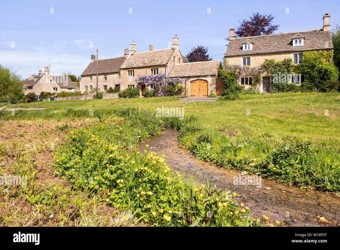 Ein Strom fließt durch das Grün im Cotswold Dorf Little Barrington, Gloucestershire, Großbritannien Stockfoto