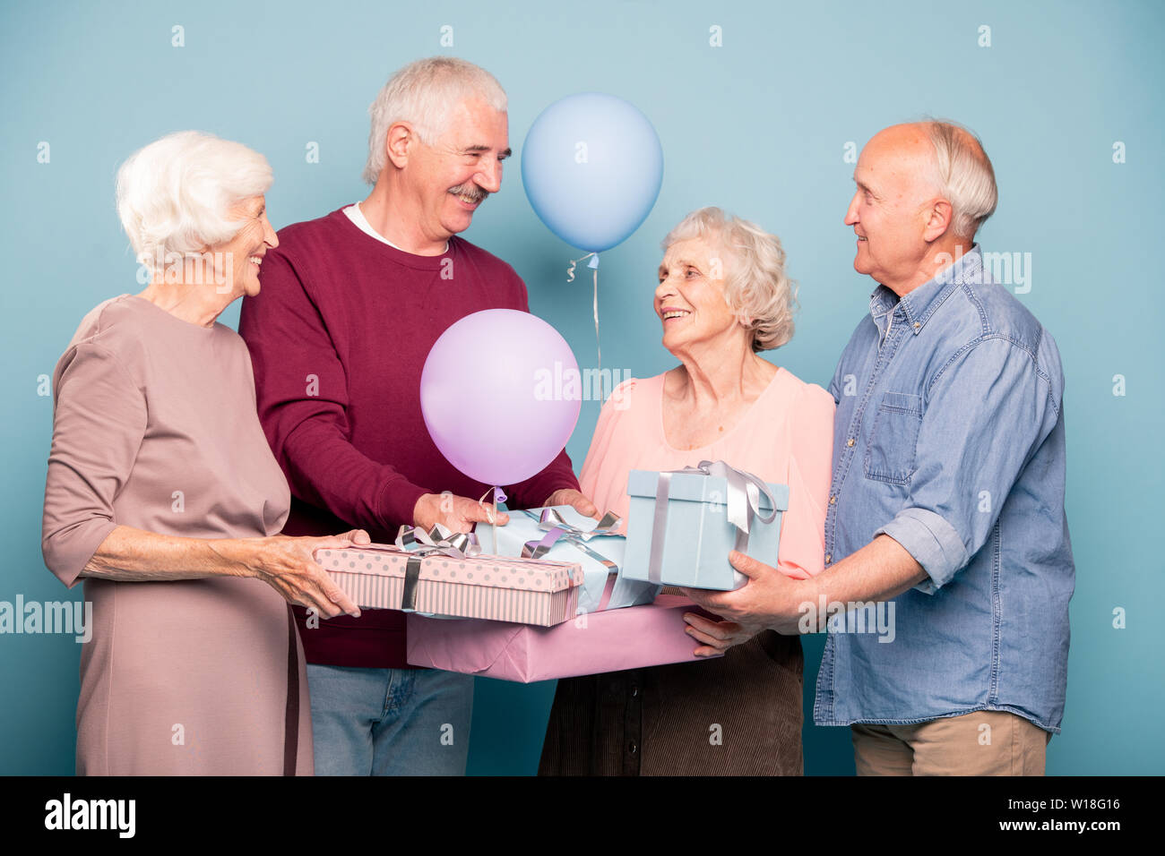 Fröhliche Gesellschaft von freundlichen Rentner mit Ballons und giftboxes Urlaub oder ein Jubiläum feiern. Stockfoto