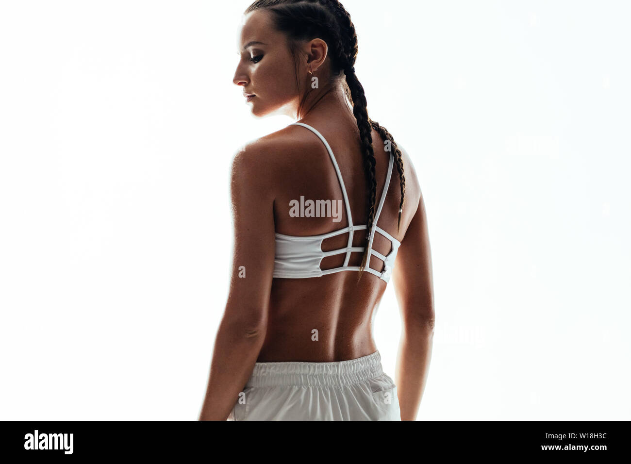 Ansicht der Rückseite des junge Frau im Sport Kleidung gegen weißen Hintergrund stehen. Weibliche fitness Model posiert im Studio. Stockfoto
