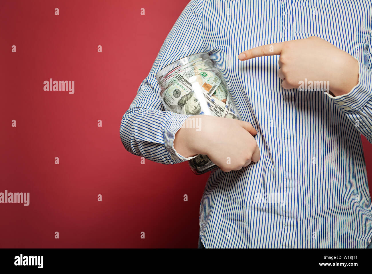 Zeigende Hand und Geld in US-Dollar in den jar auf rosa Hintergrund Stockfoto