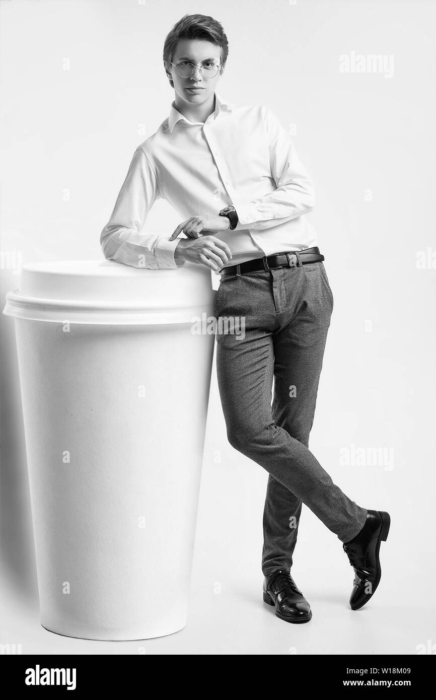 Portrait von selbstbewussten jungen gutaussehenden Geschäftsmann in Shirt mit einer riesigen Tasse Kaffee auf weißem Hintergrund posiert im Studio isoliert Stockfoto