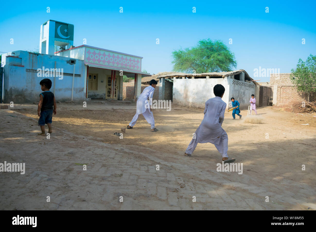 Rahimyar Khan, Punjab, Pakistan - Juli 1,2019: Einige lokalen jungen Kricket spielen in einem Dorf, batsman spielt einen Schuß, Staub fliegen. Stockfoto