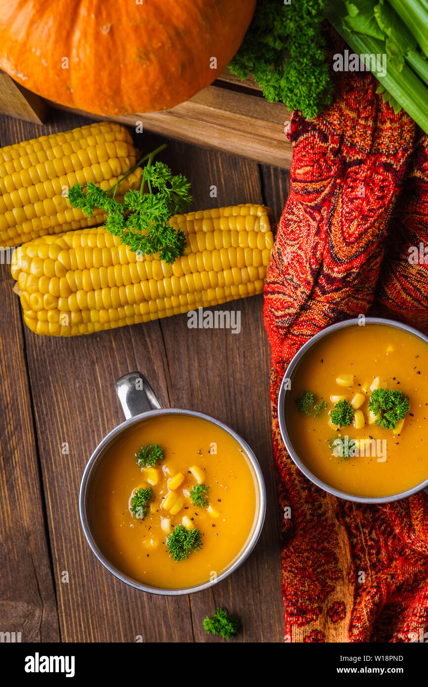 Kürbis Suppe serviert mit Mais und Petersilie und frischem Gemüse. Herbst essen Overhead shot. Stockfoto