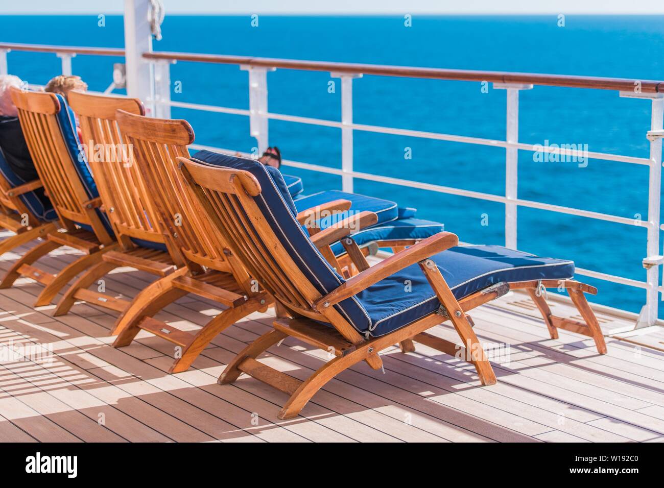 Ocean Liner Kreuzfahrt. Holzliegen und einige Touristen auf der Route zum Ziel. Stockfoto