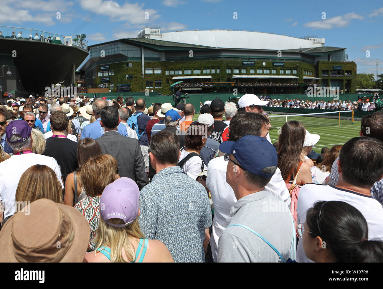 Zuschauer machen sich auf den Weg um das Grundstück am ersten Tag der Wimbledon Championships in der All England Lawn Tennis und Croquet Club, London. Stockfoto