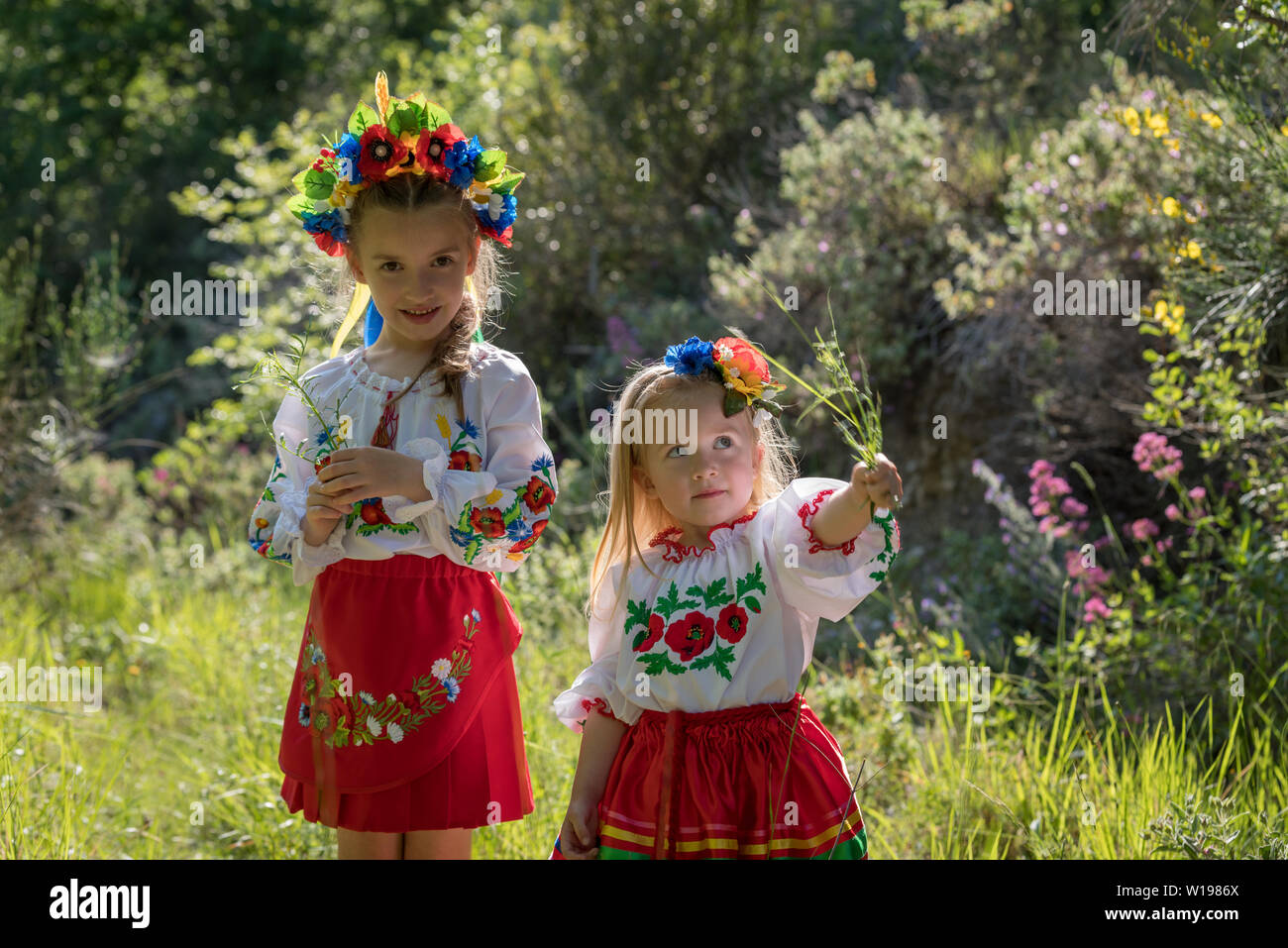 Schwestern in traditionellen ukrainischen Kostüme spielen im Frühjahr auf dem Land Stockfoto