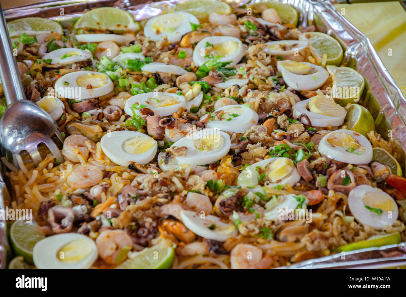 Philippinische traditionelle Gericht namens Palabok ist mit Nudeln und Meeresfrüchten, mit hartgekochten Eiern und geschnittene Limetten garniert Stockfoto
