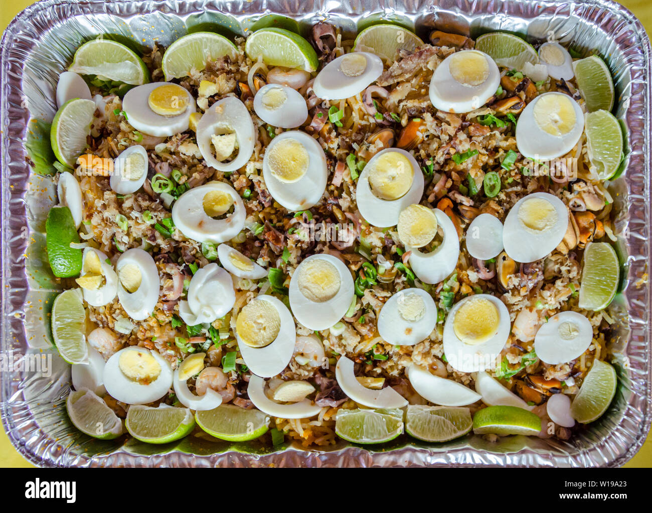 Philippinische traditionelle Gericht namens Palabok ist mit Nudeln und Meeresfrüchten, mit hartgekochten Eiern und geschnittene Limetten garniert Stockfoto