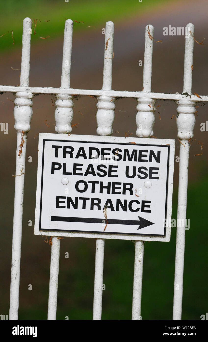 "Handwerker verwenden Sie bitte andere Eingang' Zeichen auf weißem Eisen Zaun. Stockfoto