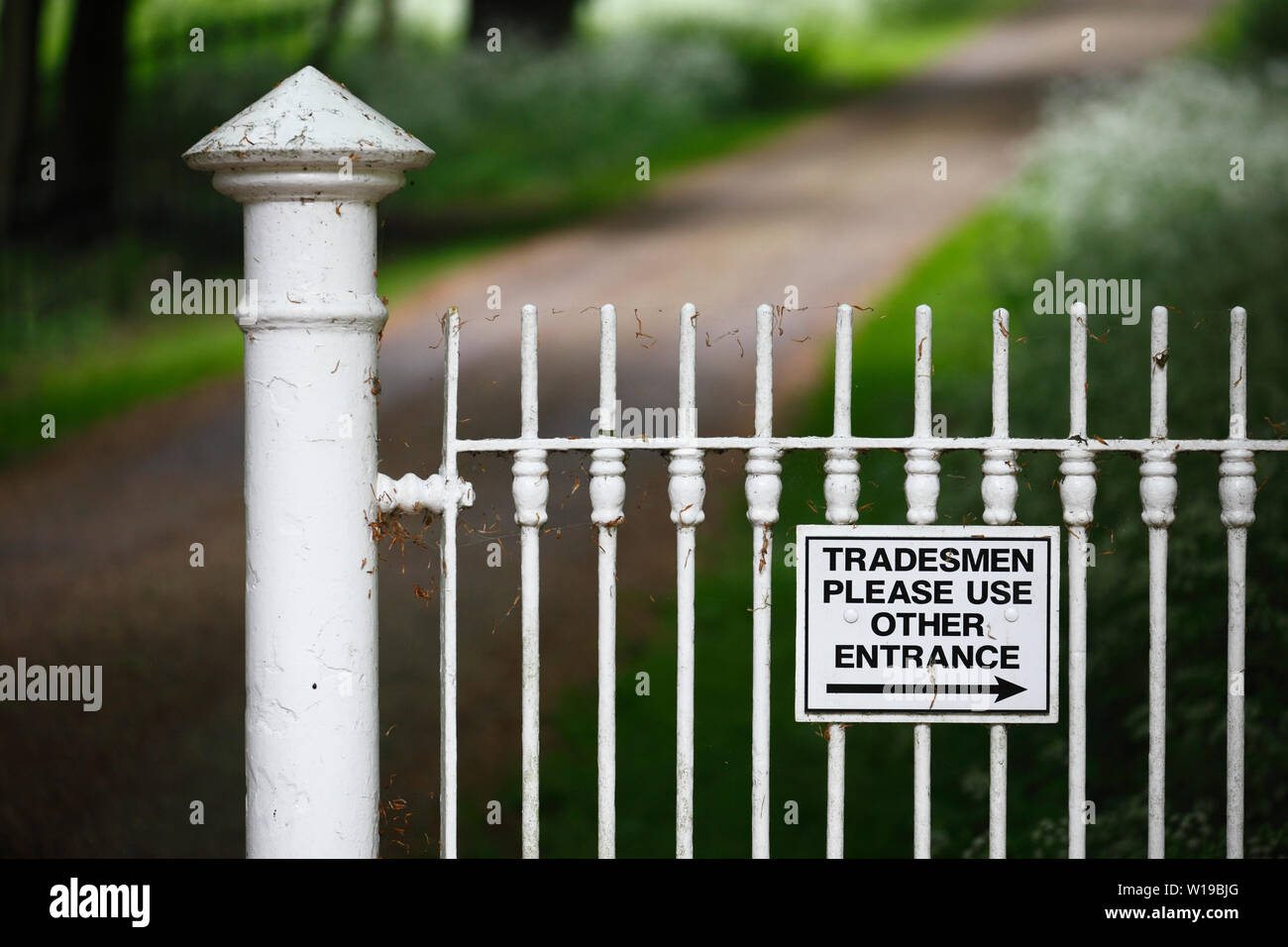 "Handwerker verwenden Sie bitte andere Eingang' Zeichen auf weißem Eisen Zaun. Stockfoto