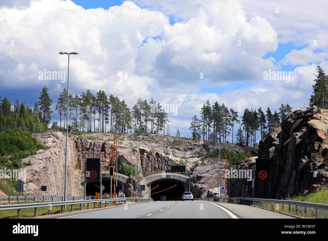 Freeway Landschaft von E 18 im Süden Finnlands mit Tunnel vor, mit langsamen Verkehr, blauer Himmel und weiße Wolken. Stockfoto