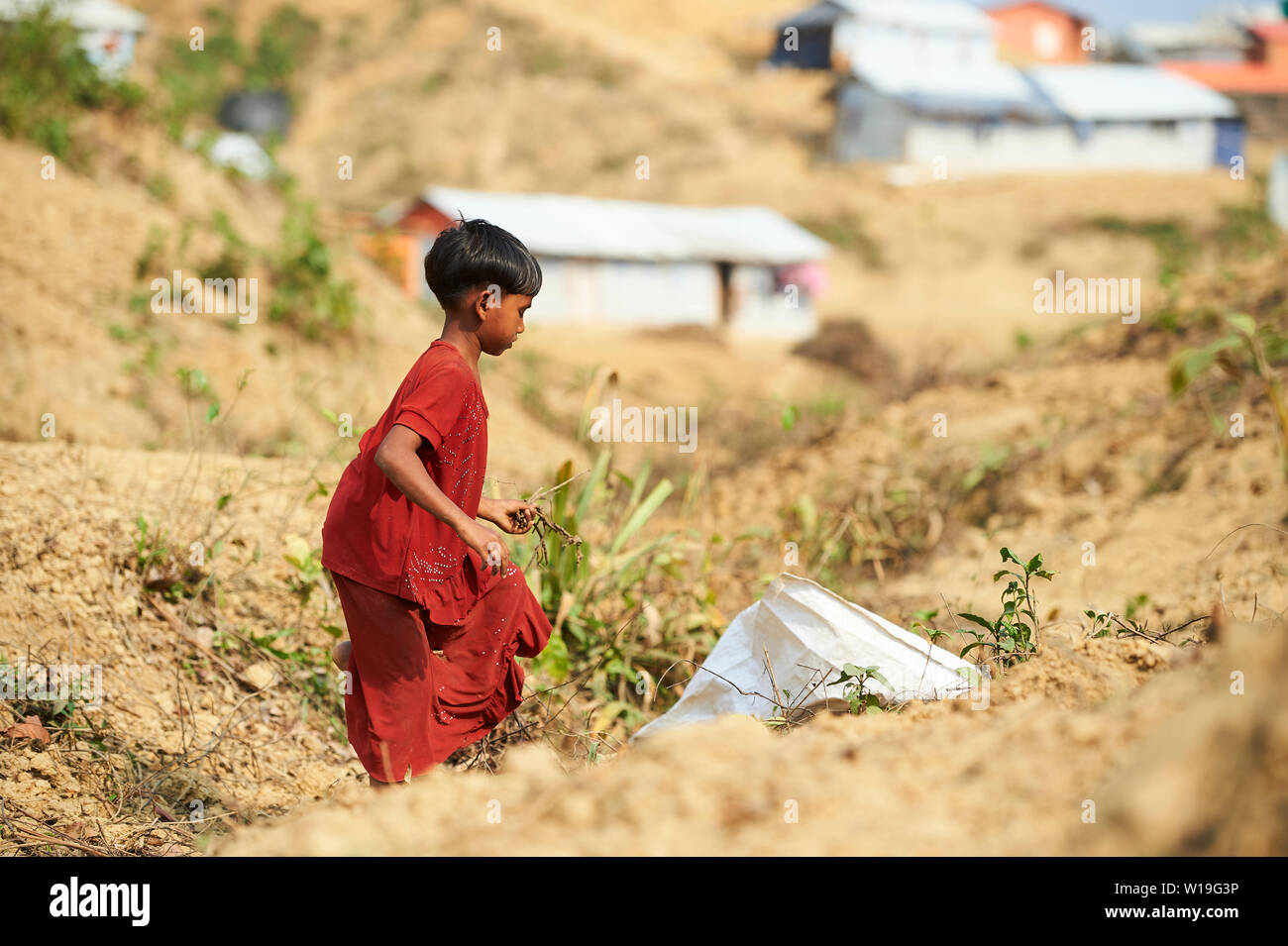 Kind im roten Kleid Sammeln von Brennholz in der Rohingya Flüchtlingslager Kutupalong, Bangladesch Stockfoto