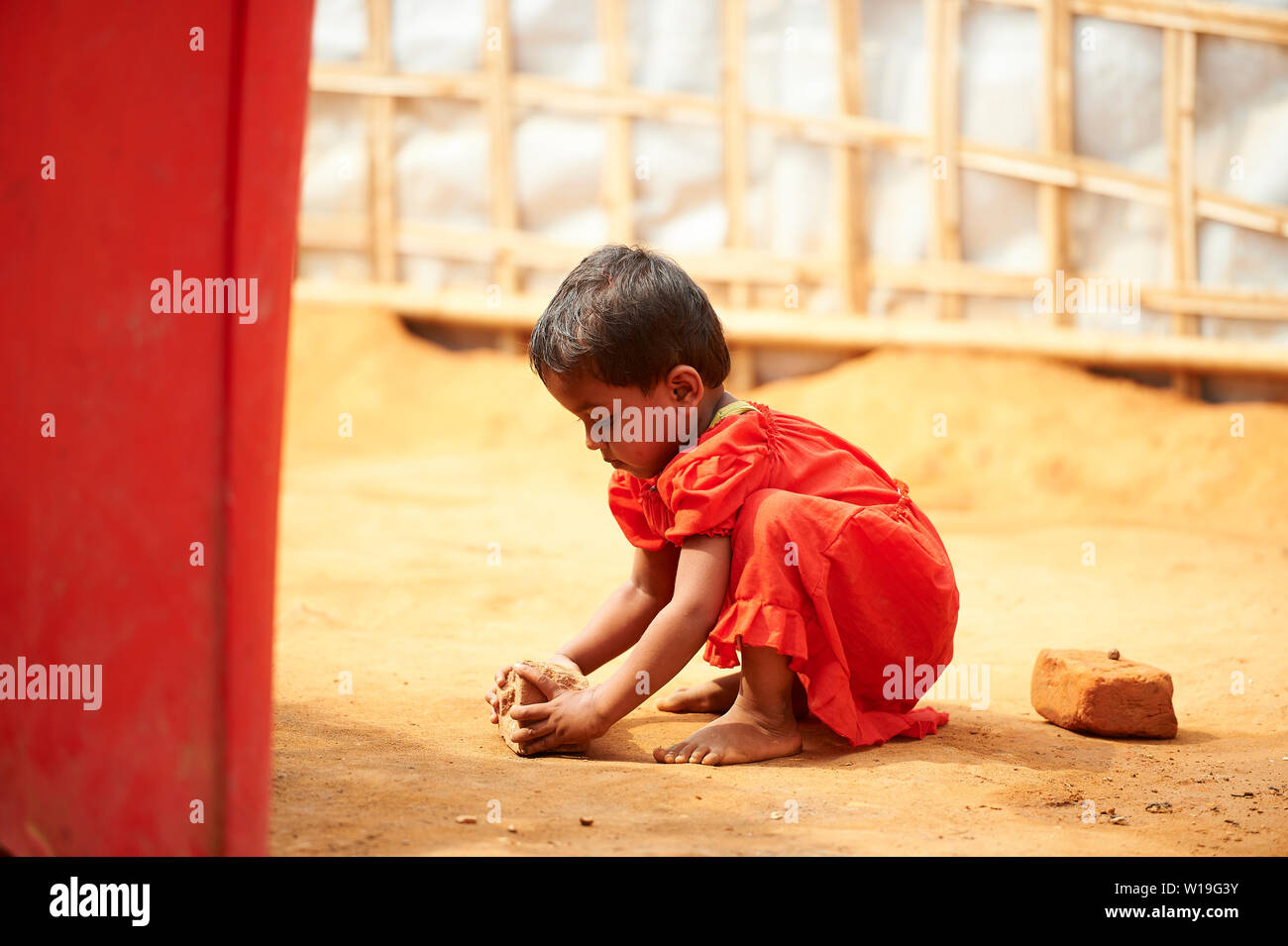 Kind im roten Kleid brechen die Muttern in der Rohingya Flüchtlingslager Kutupalong, Bangladesch Stockfoto