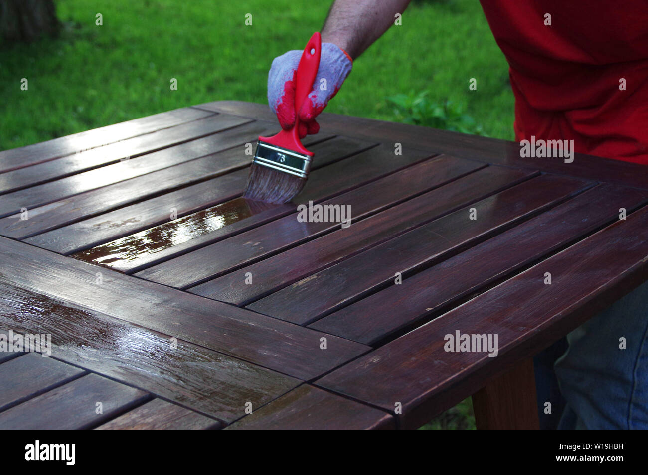Gartenmöbel Pinsel malen. Hand malen der hölzernen Tisch outdoor. Stockfoto