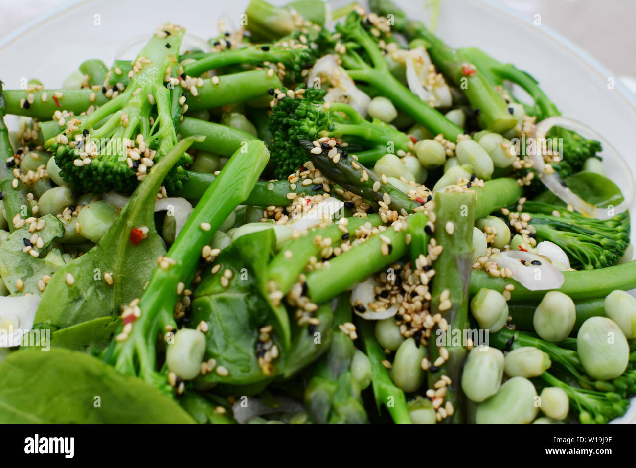 Lecker Frühjahr Salat von Baby, Brokkoli, Spargel, Bohnen, Spinat Blätter und Schalotte mit Sesam und Nigellasamen gekleidet Stockfoto