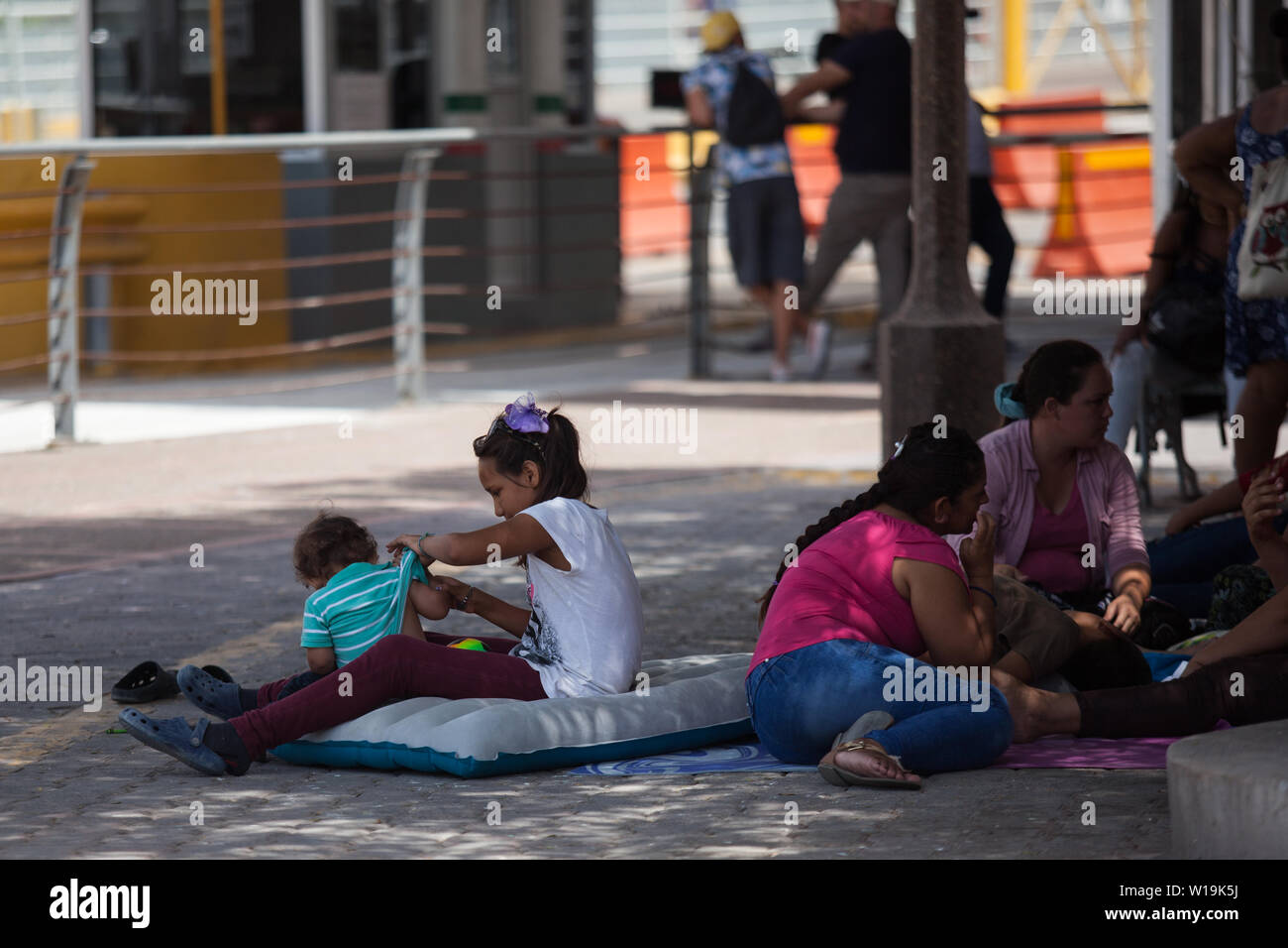 Matamoros, Mexiko. 30. Juni, 2019. Ein Mädchen sitzt neben ihr kleiner Bruder auf einer aufblasbaren Matratze in der Nähe des Puerta Mexiko Brücke. Hunderte von Migranten warten in der Nähe der Internationalen Brücke, Asyl für die Vereinigten Staaten zu beantragen. Die Atmosphäre ist hoffnungslos, wie viele Migranten im Freien in der Mitte der hohen Temperaturen, die in der Gemeinschaft auf den Norden Mexikos Grenze herrschen, Leben. Credit: Carlos Ogaz/dpa/Alamy leben Nachrichten Stockfoto