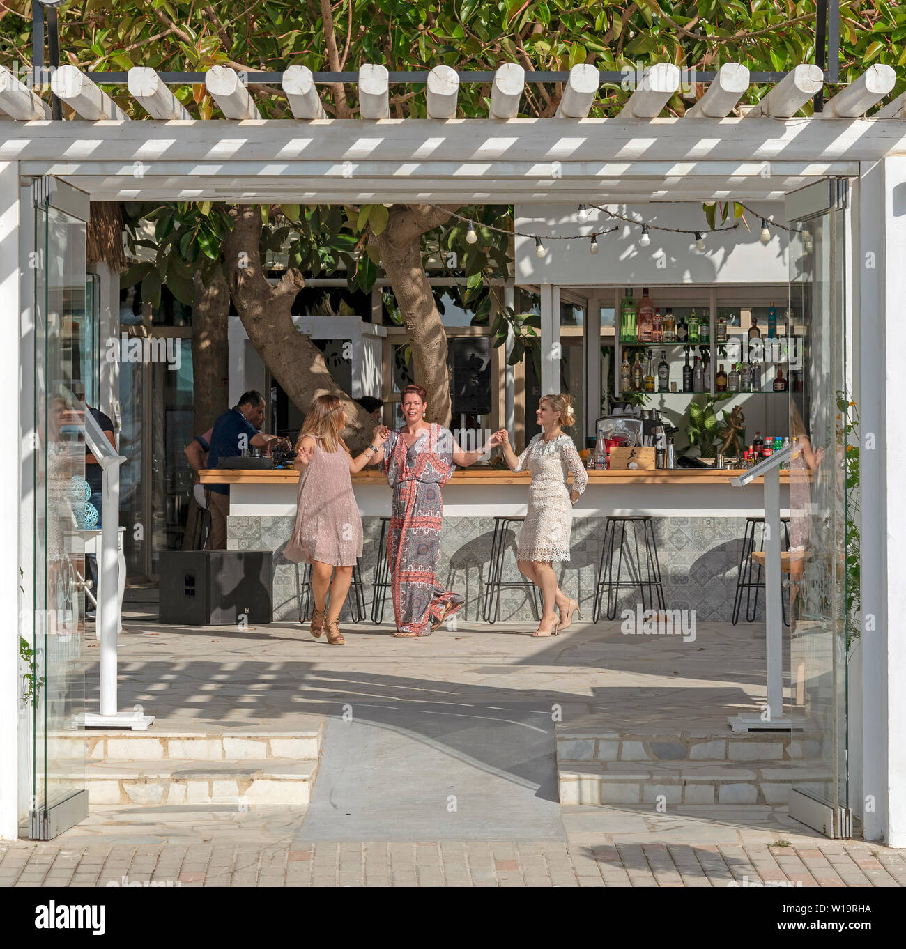 Chania, Kreta, Griechenland. Juni 2019. Kunden tanzen rund um die Bar von einem griechischen Restaurant in der Gegend von Chania auf Kreta. Stockfoto