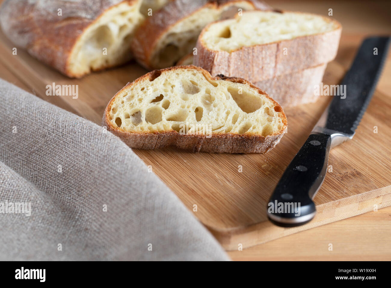 Scheibe Rustikales Brot auf Schneidebrett mit Messer Stockfoto