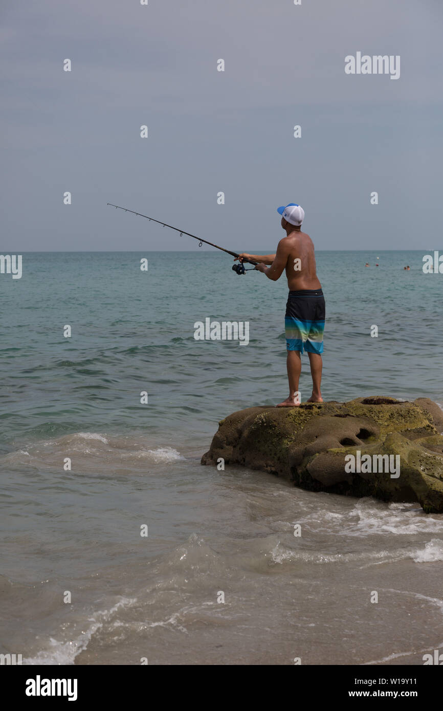 Ein junger Mann Fische aus der felsigen Atlantik Strand bei Carlin Park in Jupiter, Florida, USA. Stockfoto