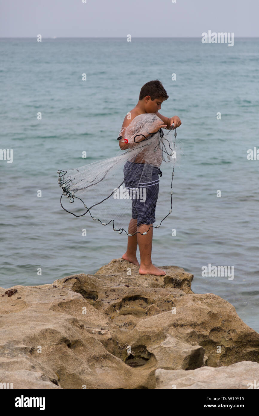 Ein Teenager wirft sein Netz als er Fische aus der felsigen Atlantik Küste bei Carlin Park in Jupiter, Florida, USA. Stockfoto