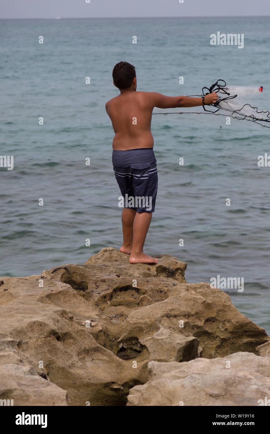 Ein Teenager wirft sein Netz als er Fische aus der felsigen Atlantik Küste bei Carlin Park in Jupiter, Florida, USA. Stockfoto