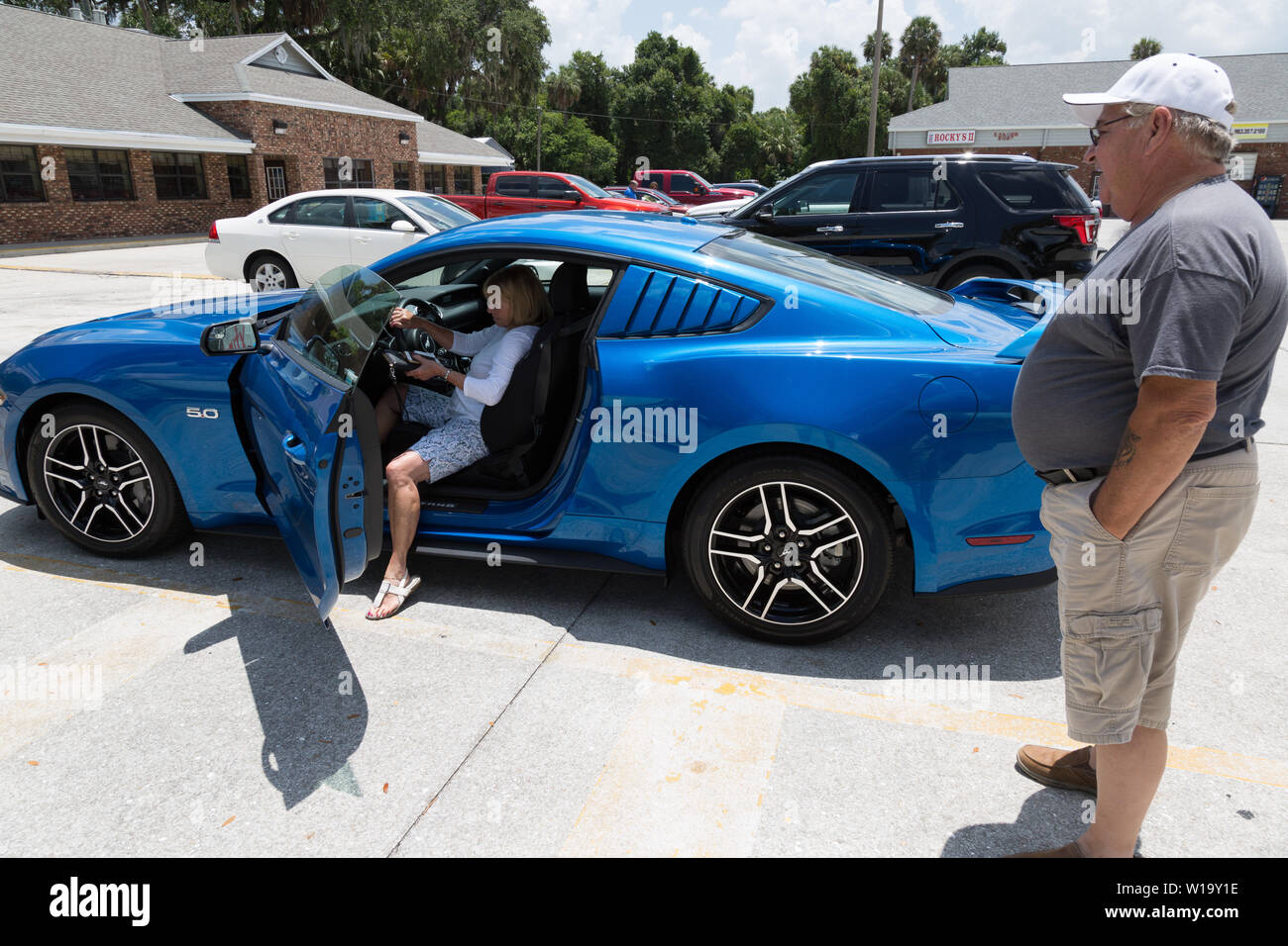 Eine Frau präsentiert ihr neues blaues 2019 Ford Mustang GT Fastback Coupé in Okeechobee, Florida, USA. Stockfoto