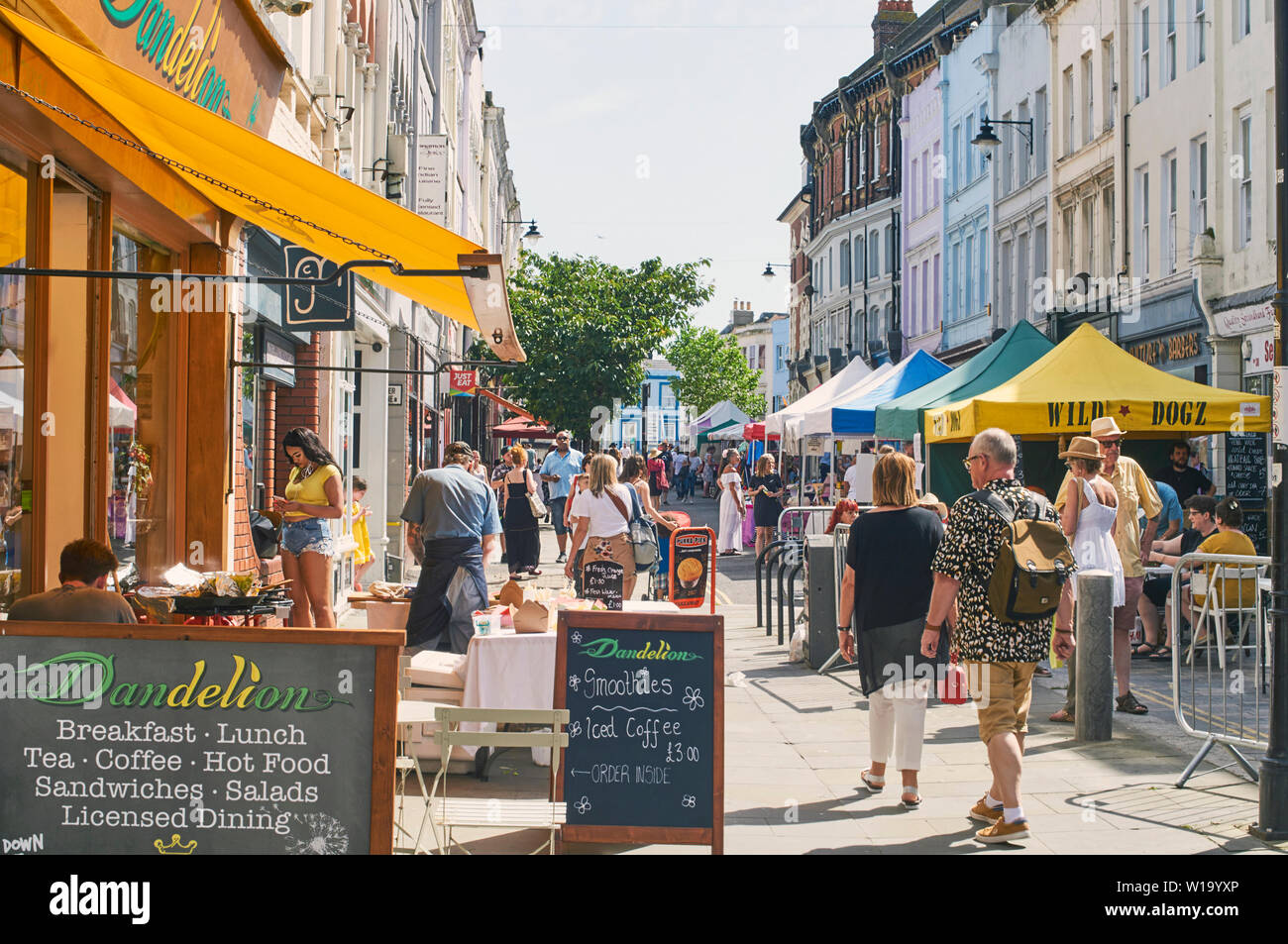 Cafes und Geschäften in der Kings Road, St Leonards on Sea, East Sussex, mit der Kings Road Street Market im Juni, und Fußgänger Stockfoto