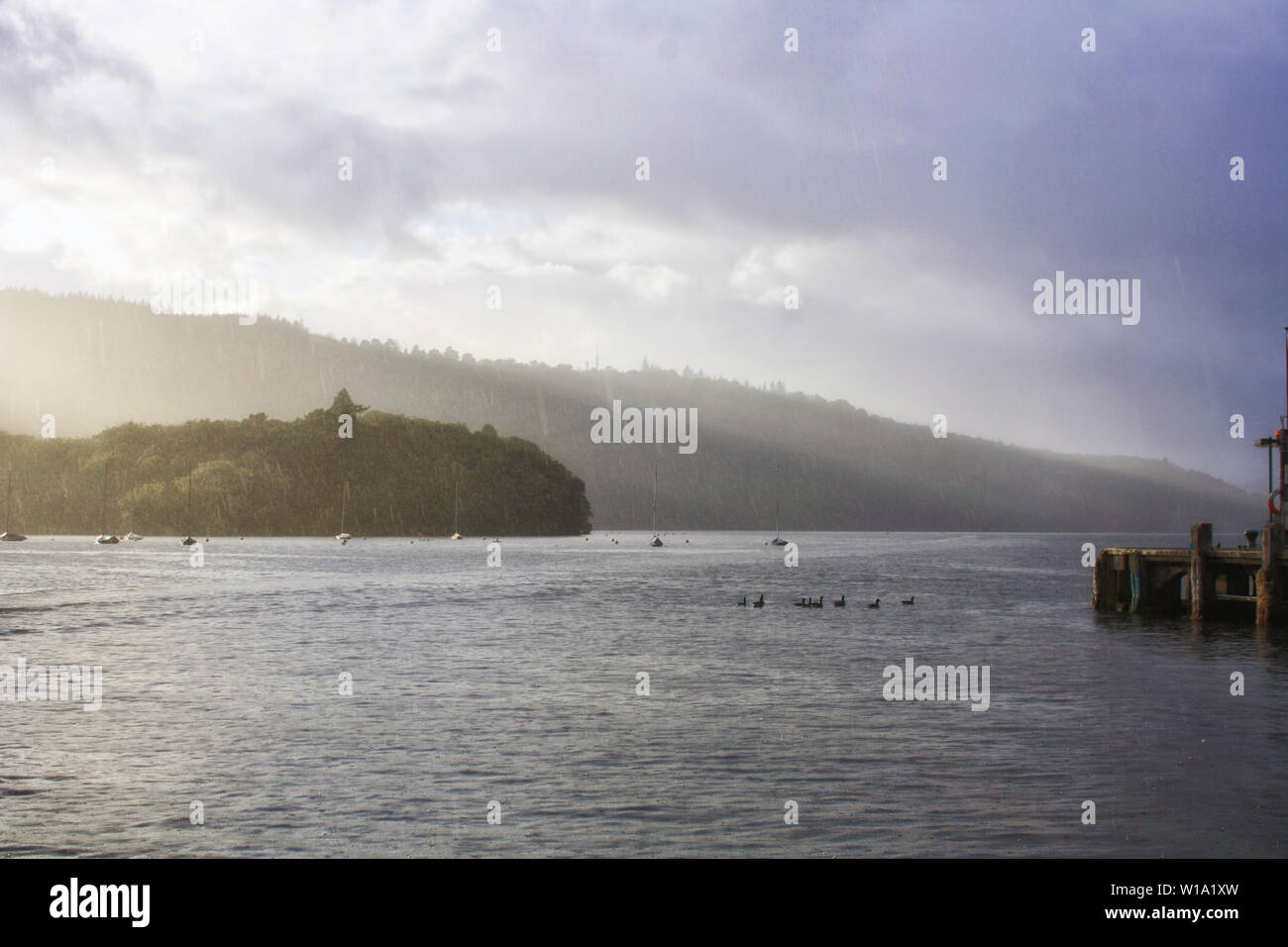 Eine sehr eindrucksvolle Aussicht auf den See Windermere bei einem leichten Regenguss mit ein paar Sonnenstrahlen durch die Wolken. Lake District National Park. Stockfoto